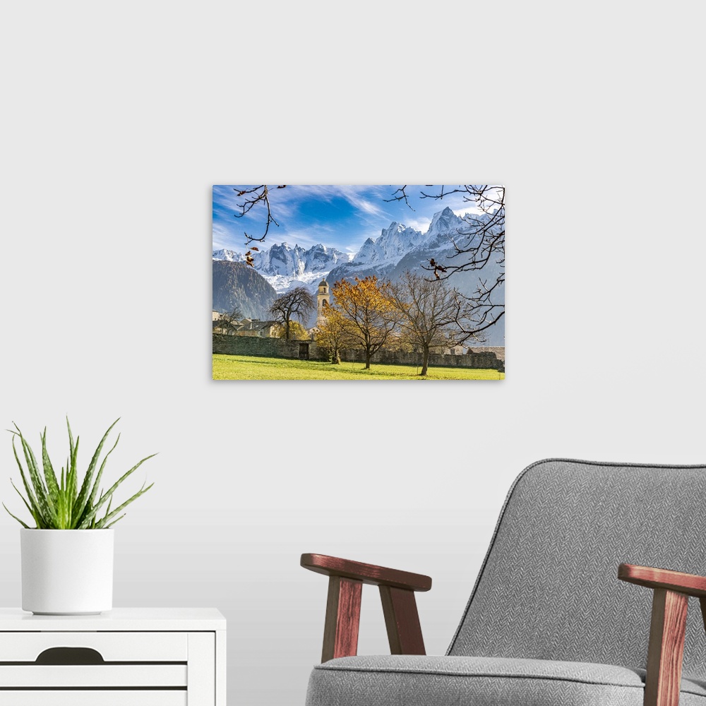 A modern room featuring Old church lit by autumn colors with snowcapped Piz Badile and Cengalo in the background, Soglio,...
