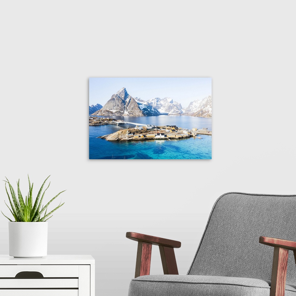 A modern room featuring Aerial view of Olstind mountain peak and turquoise sea surrounding Sakrisoy village and Reine Bay...