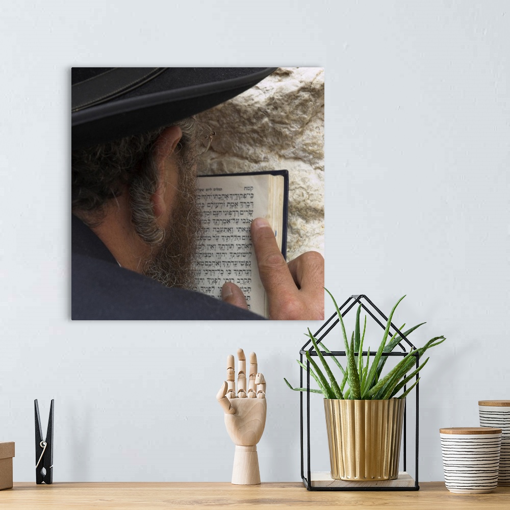 A bohemian room featuring Close up of an Orthodox Jew holding prayer book against the wall and praying, Western Wall, Jerus...