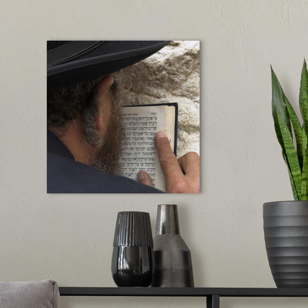 A modern room featuring Close up of an Orthodox Jew holding prayer book against the wall and praying, Western Wall, Jerus...