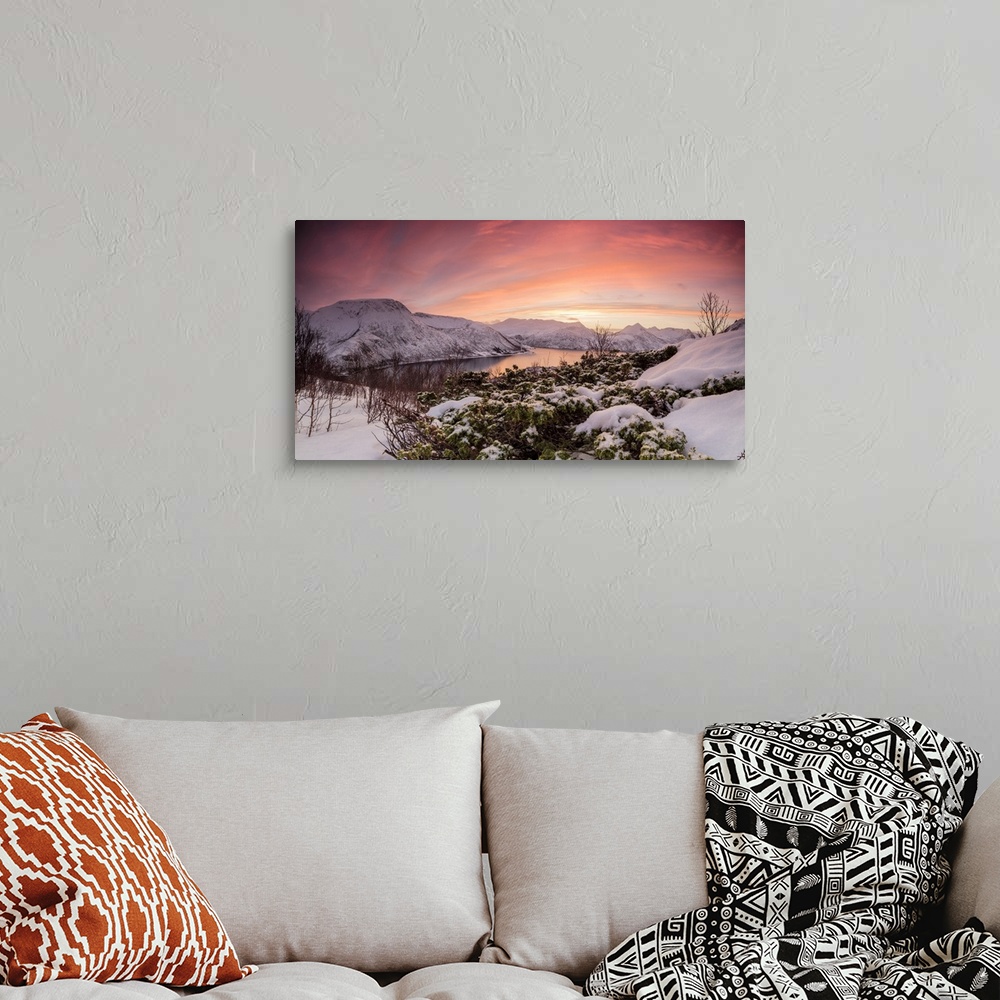 A bohemian room featuring Panorama of frozen sea surrounded by snow framed by the orange sky at sunset, Torsken, Senja, Tro...