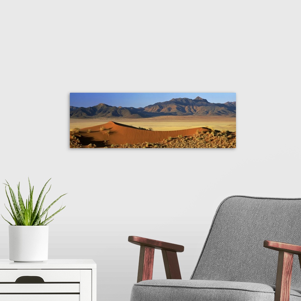 A modern room featuring Panoramic view over orange sand dunes towards mountains, Namibia, Africa