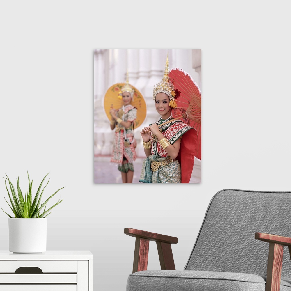 A modern room featuring Portrait of two dancers in traditional Thai classical dance costume, smiling and looking at the c...