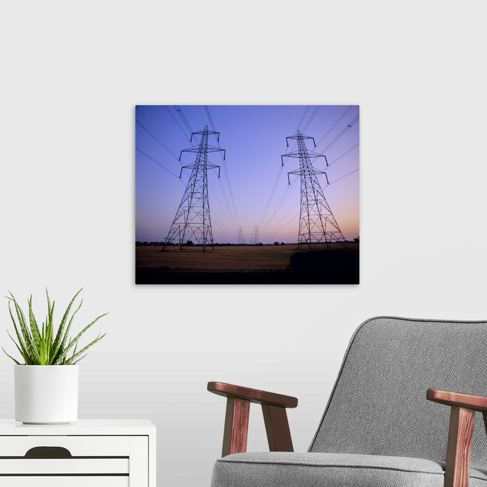 A modern room featuring Pylons in a rural landscape at dusk