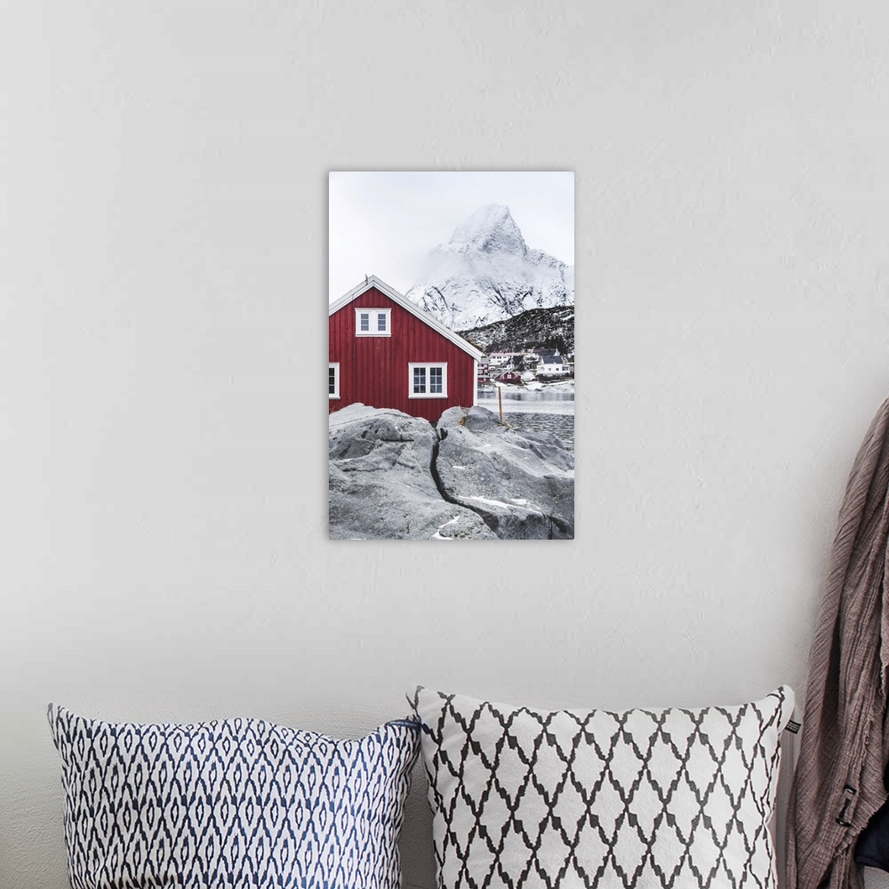 A bohemian room featuring Red Rorbu in the frozen landscape with snowcapped Olstind mountain in the background, Reine, Nord...