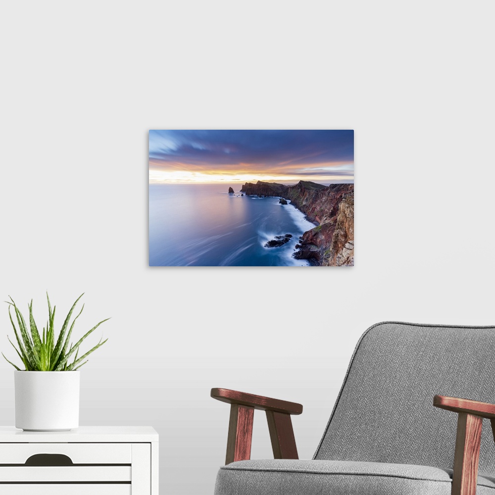 A modern room featuring Dramatic sky at dawn on cliffs washed by ocean from Ponta Do Rosto viewpoint, Sao Lourenco Penins...