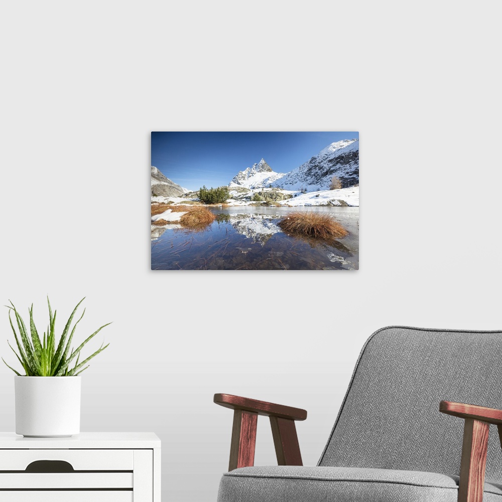 A modern room featuring Snowy peaks are reflected in the alpine lake partially frozen, Lejets Crap Alv, Canton of Graubun...