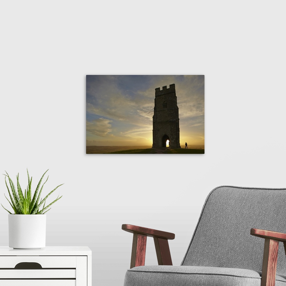 A modern room featuring St. Michael's Tower silhouetted at sunset, on the summit of Glastonbury Tor, Glastonbury, Somerse...