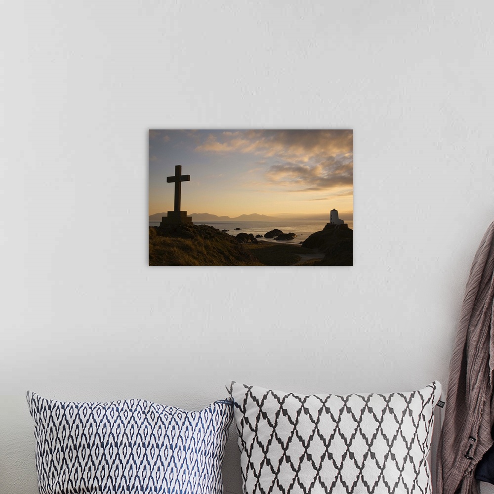 A bohemian room featuring Stone Cross and old lighthouse in silhouette at sunset, Anglesey, North Wales, UK