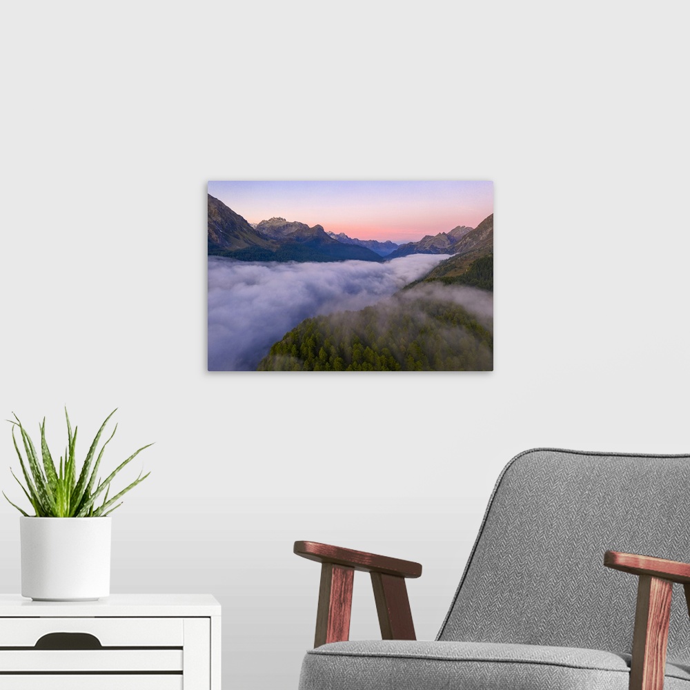 A modern room featuring Foggy sunrise over woods of Maloja Pass at dawn, aerial view by drone, Engadine, Canton of Graubu...
