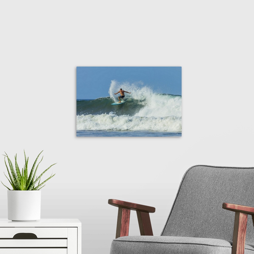 A modern room featuring Surfer on shortboard riding wave at Playa Guiones surf beach, Costa Rica