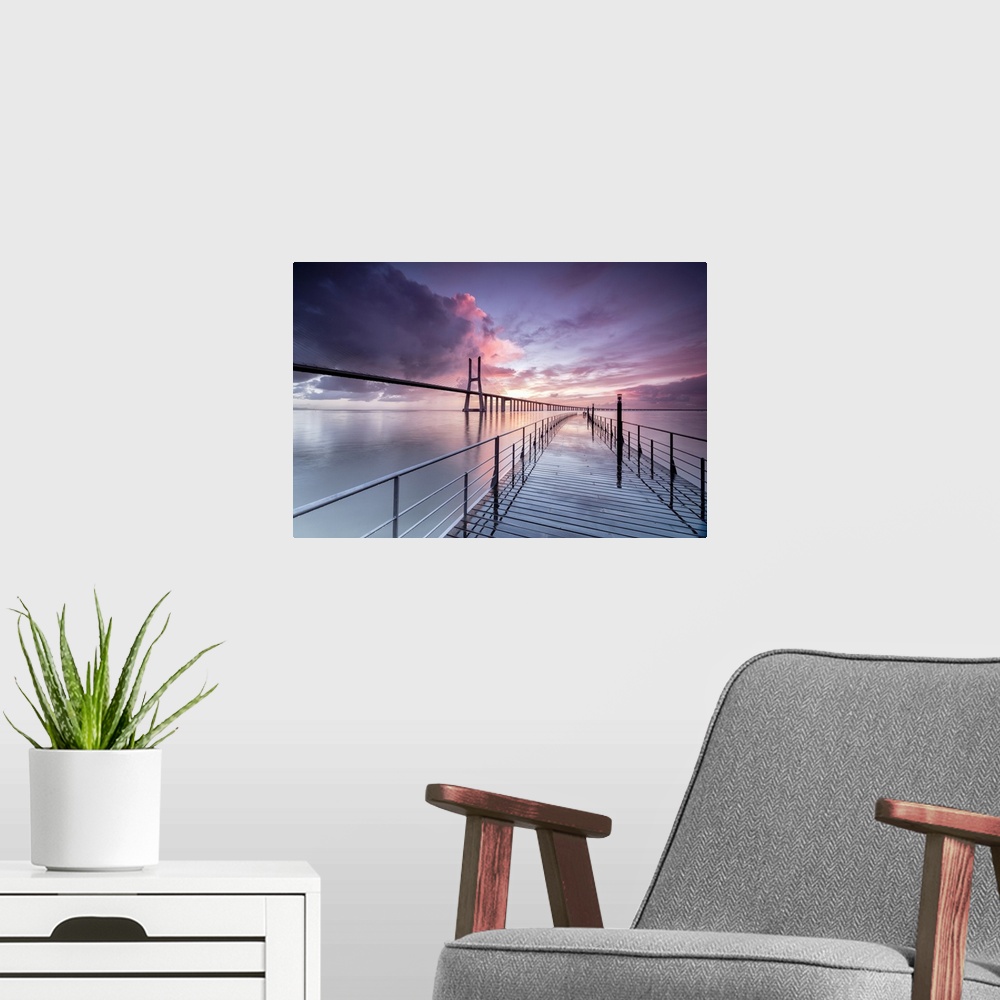 A modern room featuring Sunrise colors the clouds reflected in Tagus River and frame the Vasco da Gama bridge in Lisbon, ...