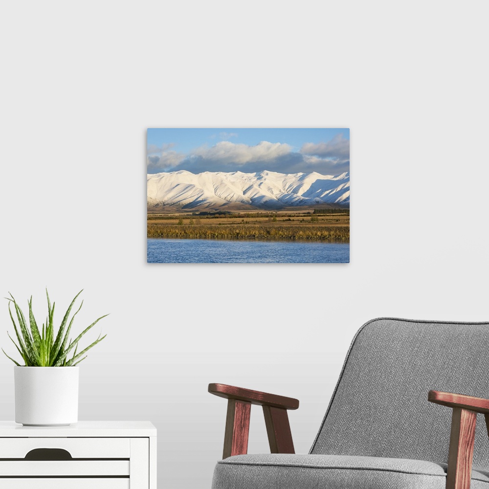 A modern room featuring The Ben Ohau Range cloaked in autumn snow, the Pukaki Canal in foreground, Twizel, Mackenzie dist...