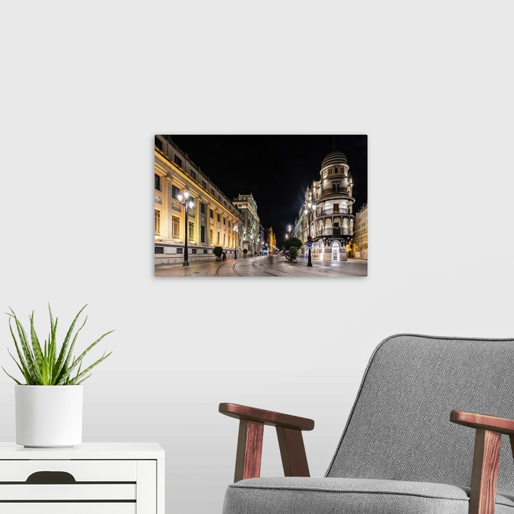 A modern room featuring The lights of Seville's buildings at night looking down the Avenida de la Constitucion towards th...