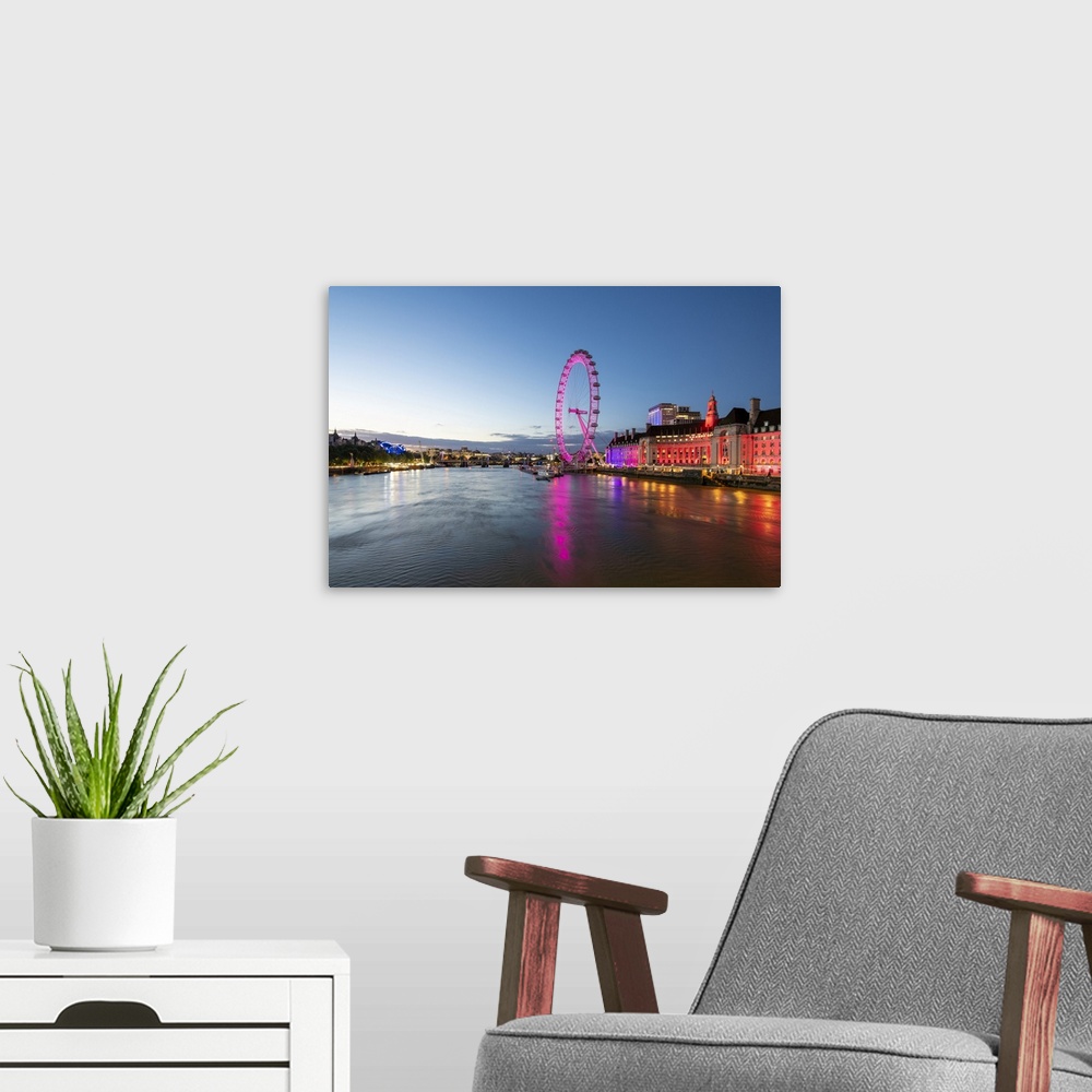 A modern room featuring The London Eye lit up pink during blue hour, and River Thames, London, England, United Kingdom, E...