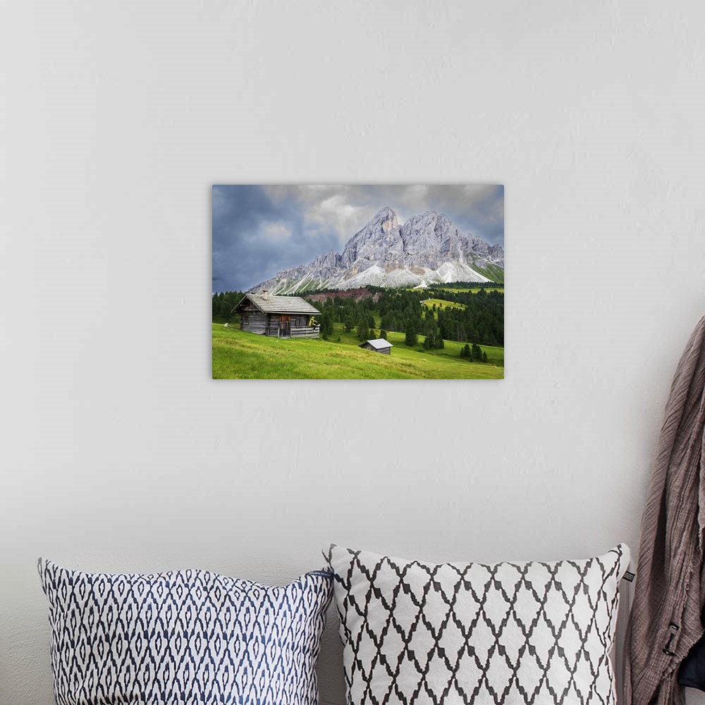 A bohemian room featuring Side view of a hiker on chalet in green meadows admiring the rocky massif of Sass de Putia, Passo...