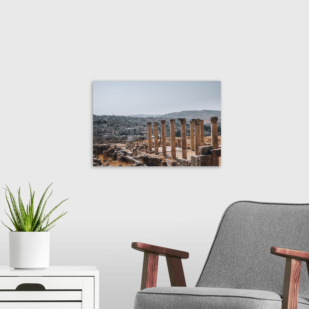 A modern room featuring The ruins of a Roman temple, with the modern city of Jerash in the background, Jerash, Jordan, Mi...