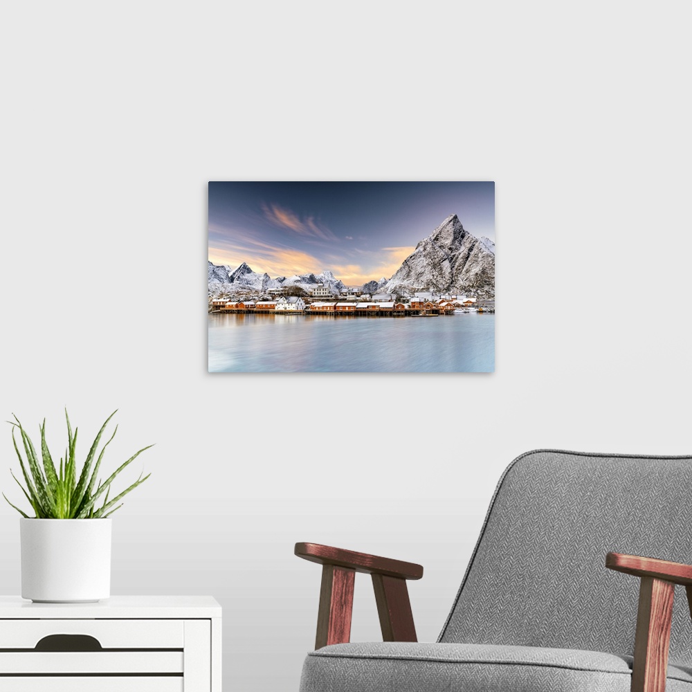A modern room featuring Winter sunset over snowcapped mountains and Sakrisoy village by the frozen sea, Reine, Nordland, ...