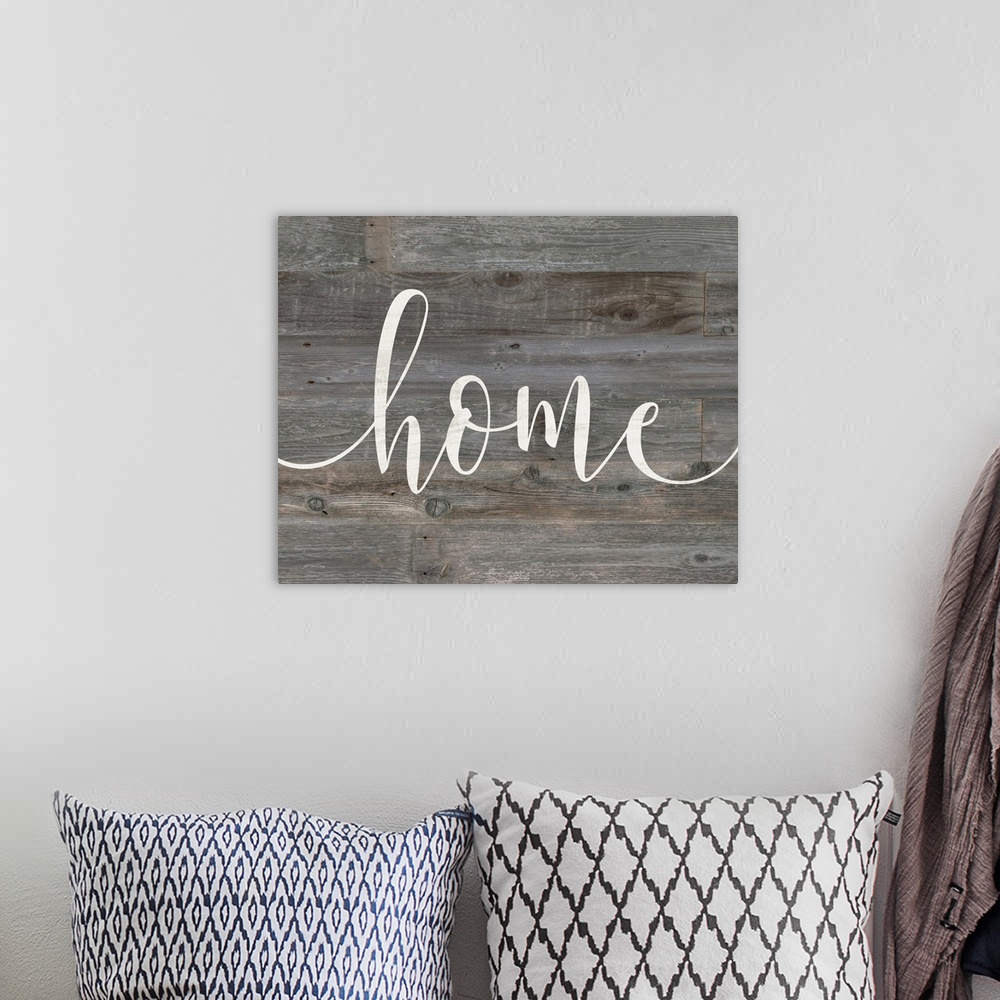 A bohemian room featuring "home" against gray shiplap wood background.