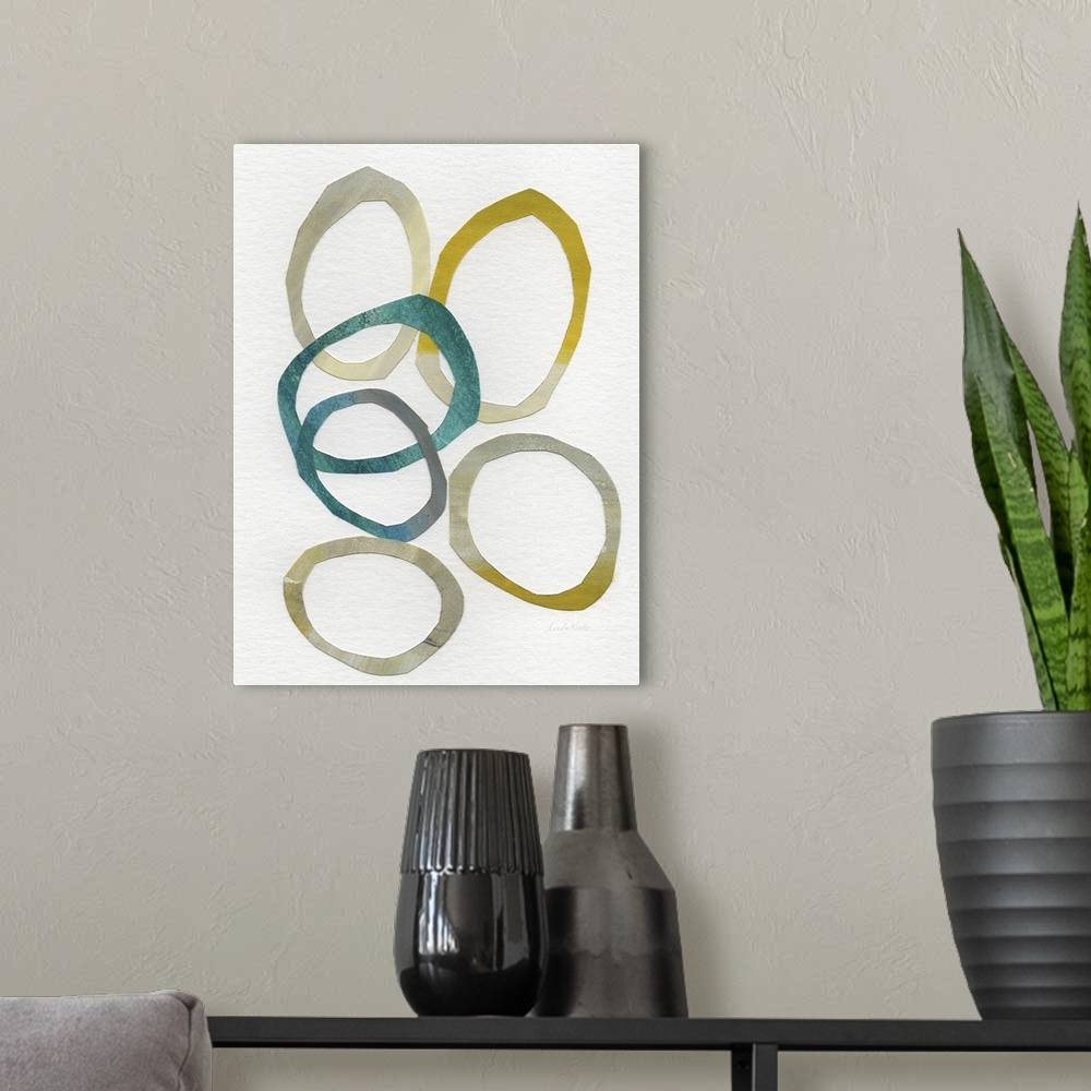A modern room featuring Abstract contemporary artwork of several overlapping rings of gold and teal, on an off-white back...