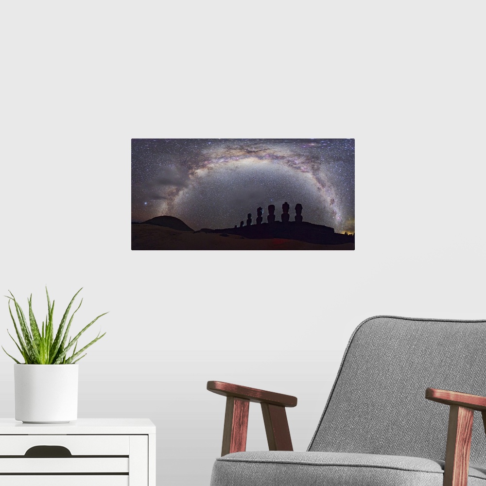 A modern room featuring Easter Island moai and Milky Way. Panoramic view of the arch of the Milky Way in the night sky ov...