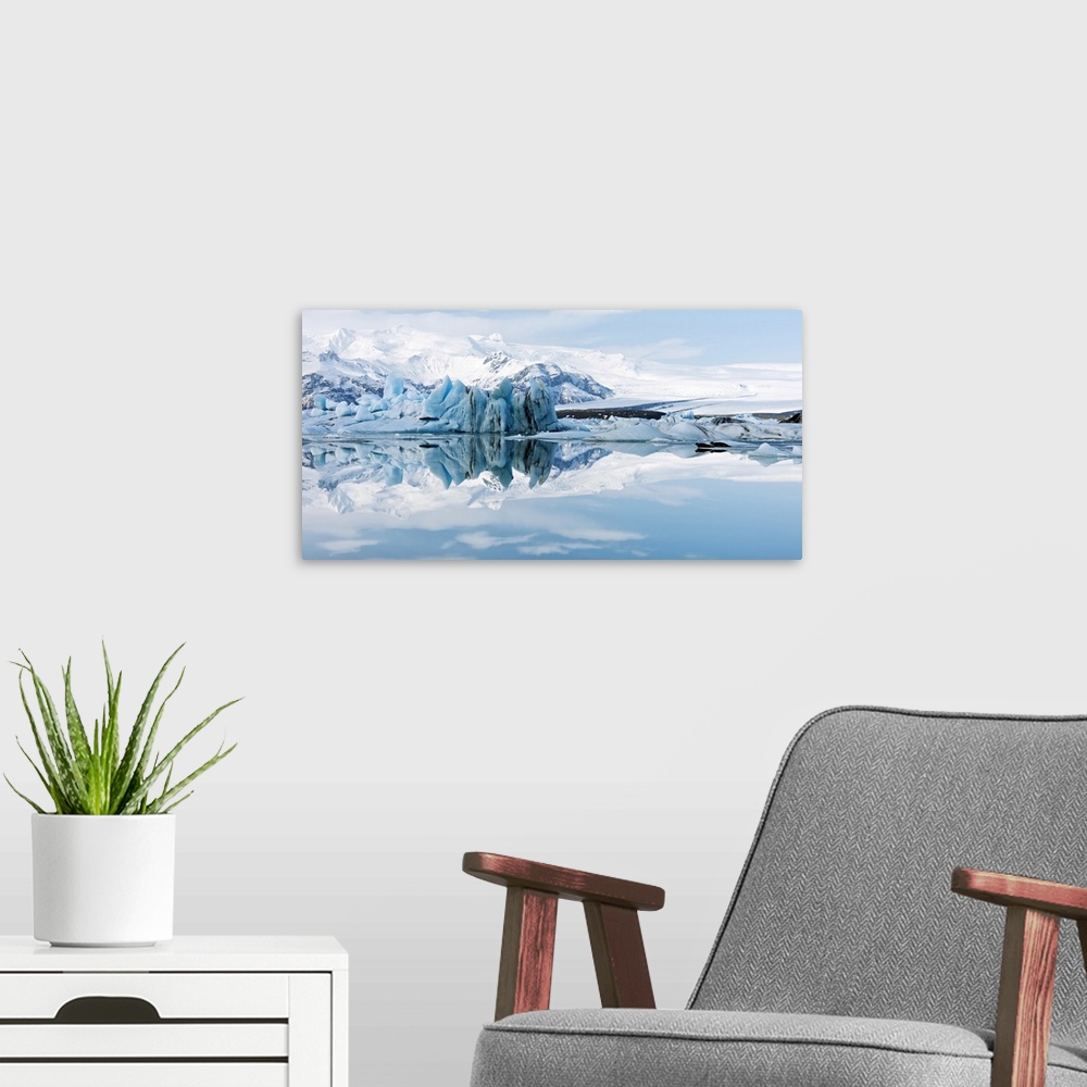 A modern room featuring Glacial coastal landscape. Mountains and ice formations reflected in the waters of a glacial lago...