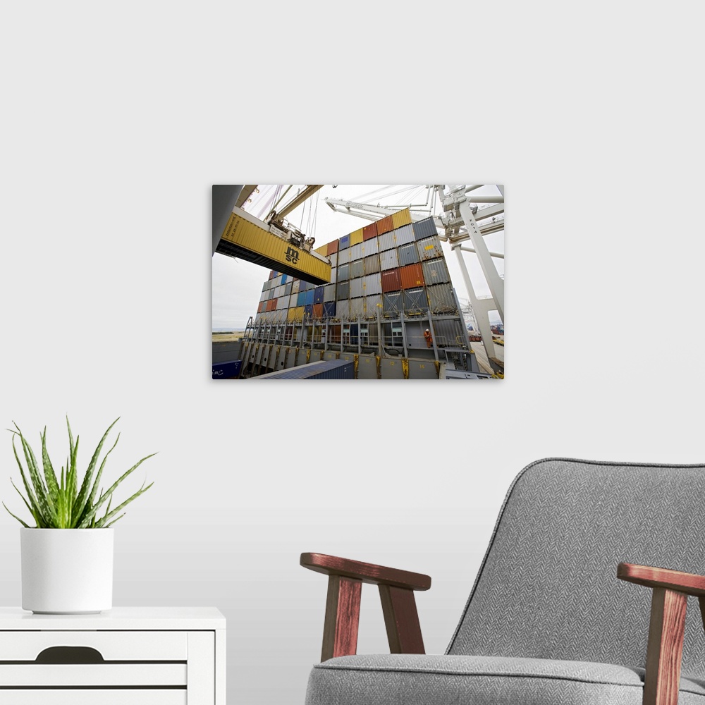 A modern room featuring Loading cargo containers. Crane being used to load a cargo container (left) onto a container ship...
