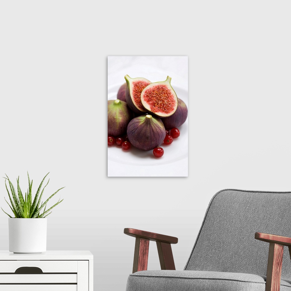 A modern room featuring Whole and halved figs on a plate. These fruits are from the fig tree (Ficus carica). The fruits a...