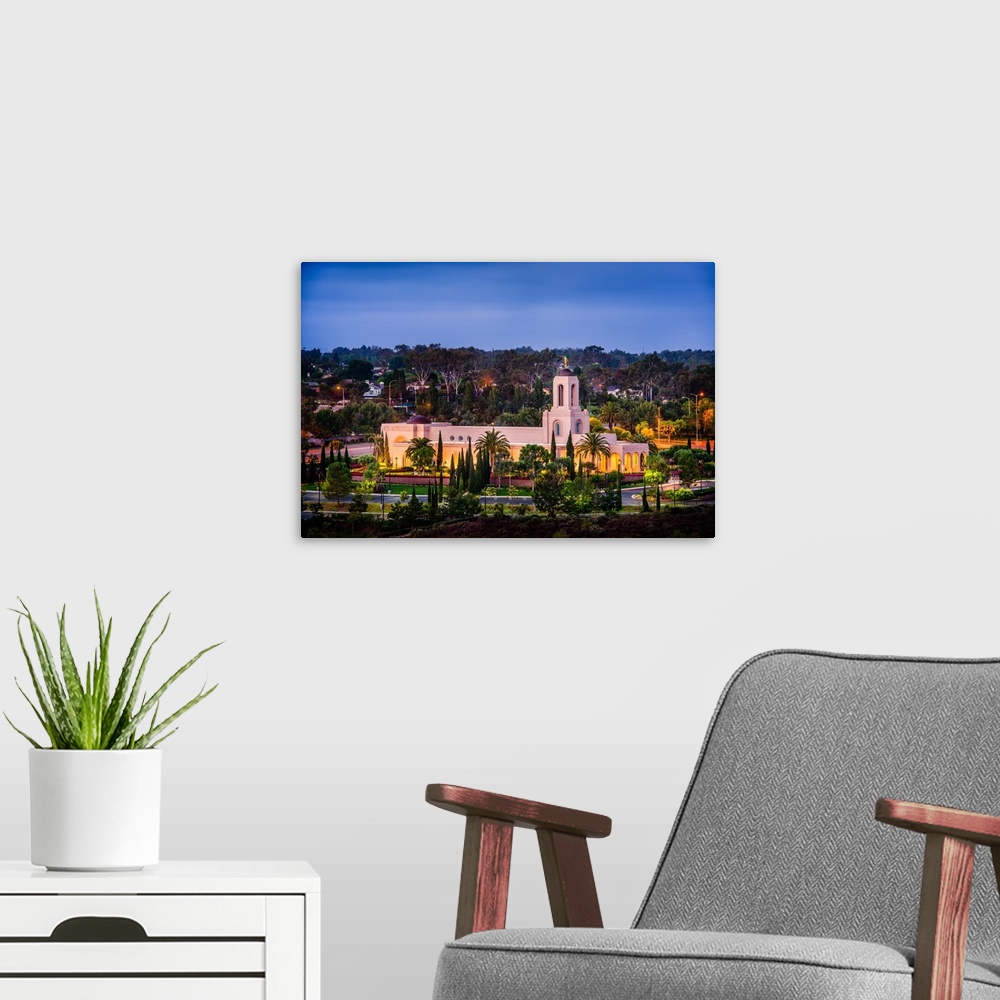 A modern room featuring The Newport Beach California Temple is surrounded by lush green grass, shrubs, and trees. It was ...
