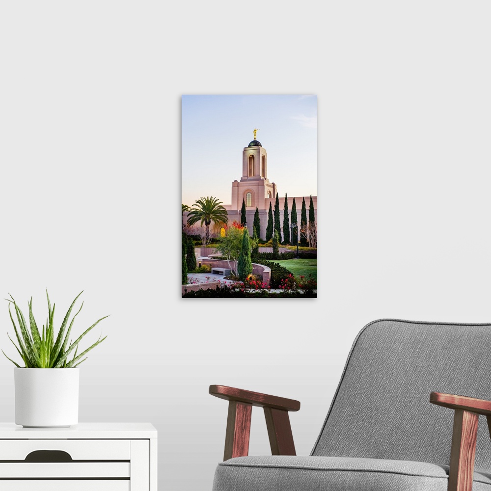 A modern room featuring The Newport Beach California Temple is surrounded by lush green grass, shrubs, and trees. It was ...