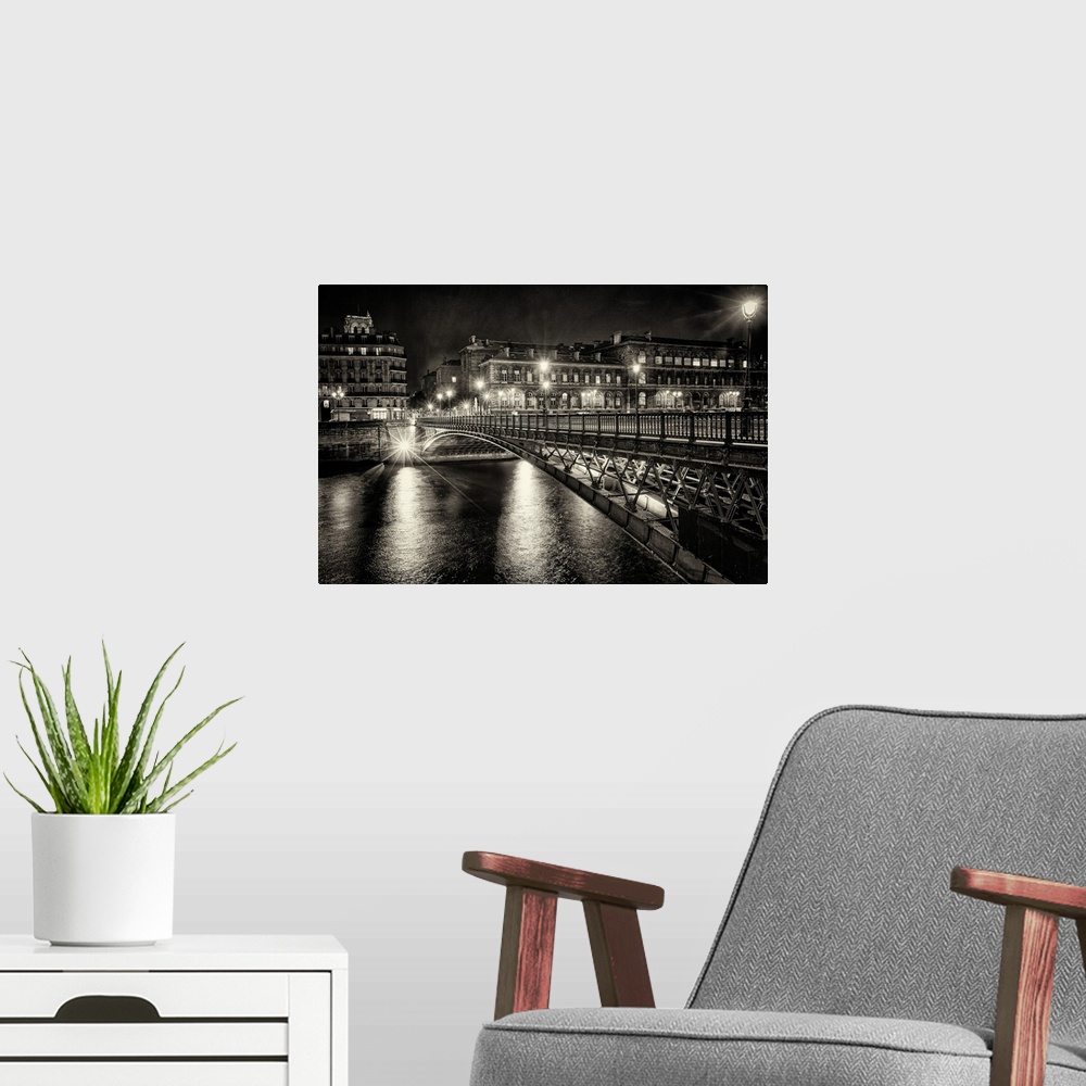 A modern room featuring High contrast photograph of a bridge crossing over the Seine River in Paris with lit up buildings...