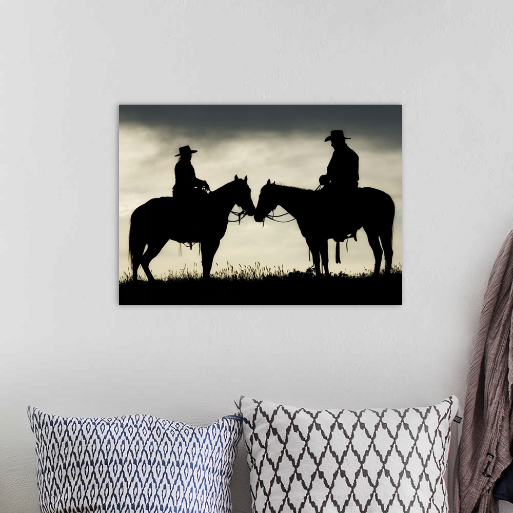 A bohemian room featuring Cowboy and cowgirl on horseback by lake at sunset