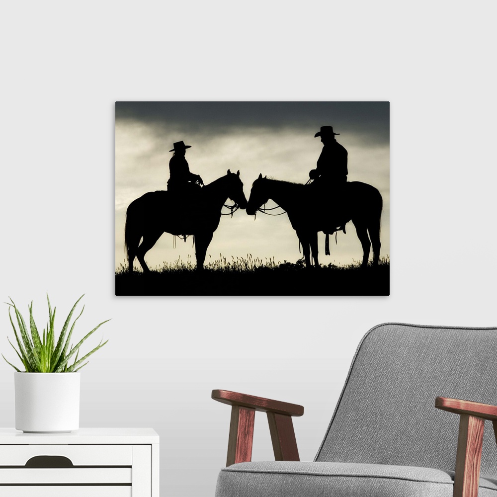A modern room featuring Cowboy and cowgirl on horseback by lake at sunset