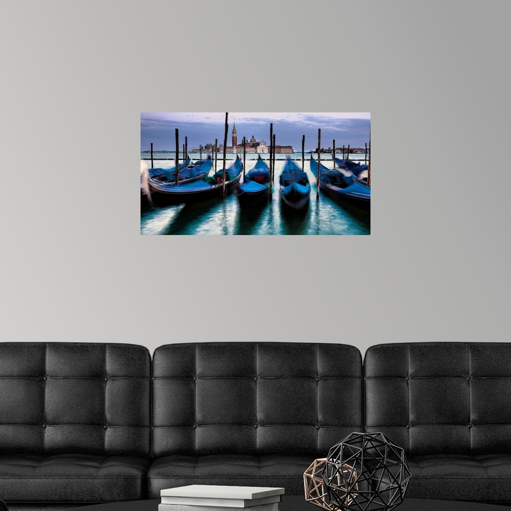 A modern room featuring Big photograph of empty gondolas tied to poles in Venice, Italy with buildings in the background.
