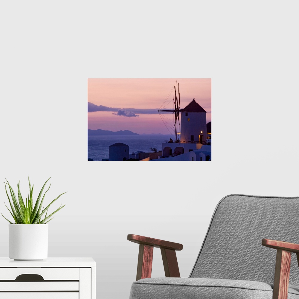 A modern room featuring Photograph of historic city lit up at dusk with  mountains in the distance under a cloudy sky.