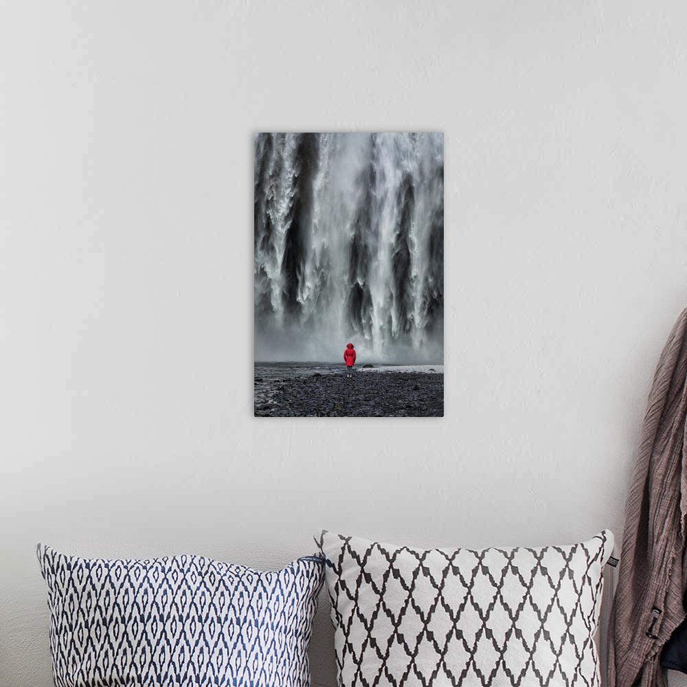 A bohemian room featuring Woman staring into Skogafoss waterfall in Iceland.