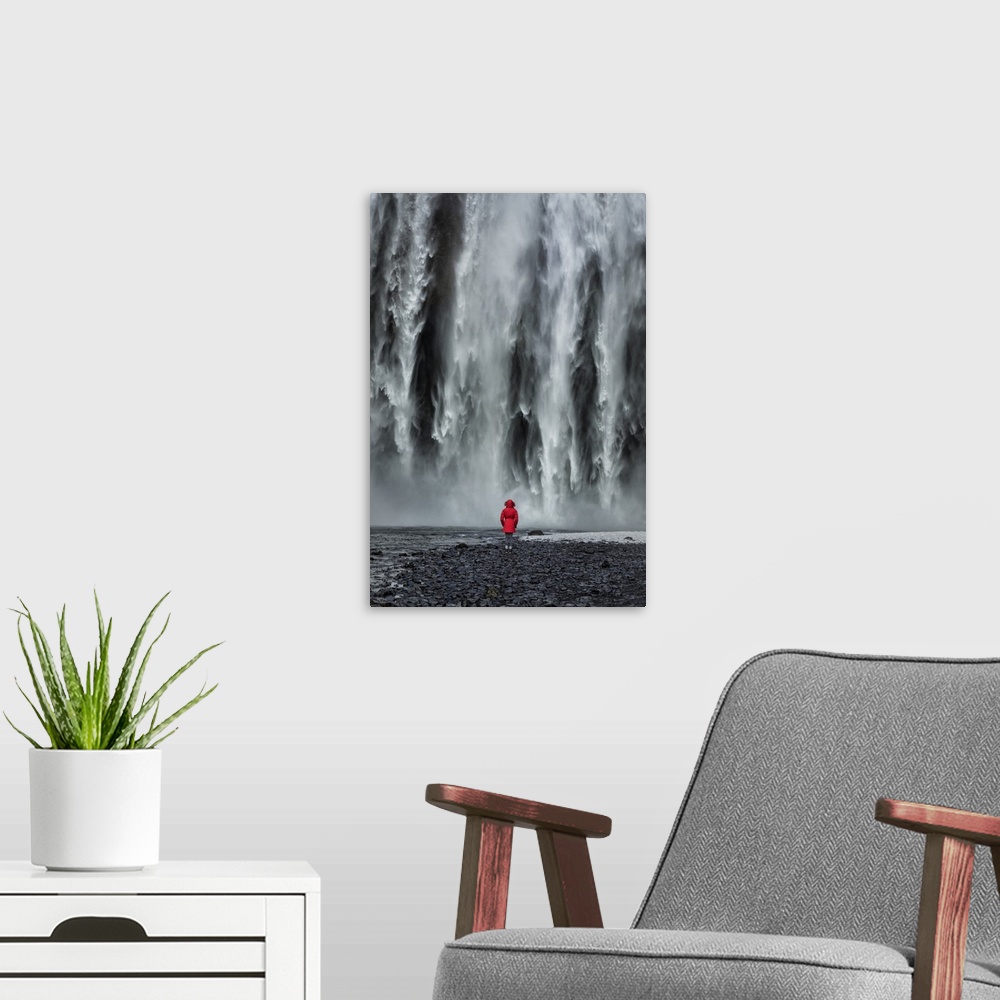 A modern room featuring Woman staring into Skogafoss waterfall in Iceland.