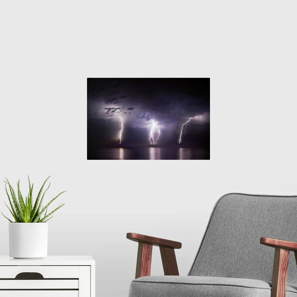 A modern room featuring Time-lapse photo of three bolts of lightning striking the ocean from storm clouds at night, illum...