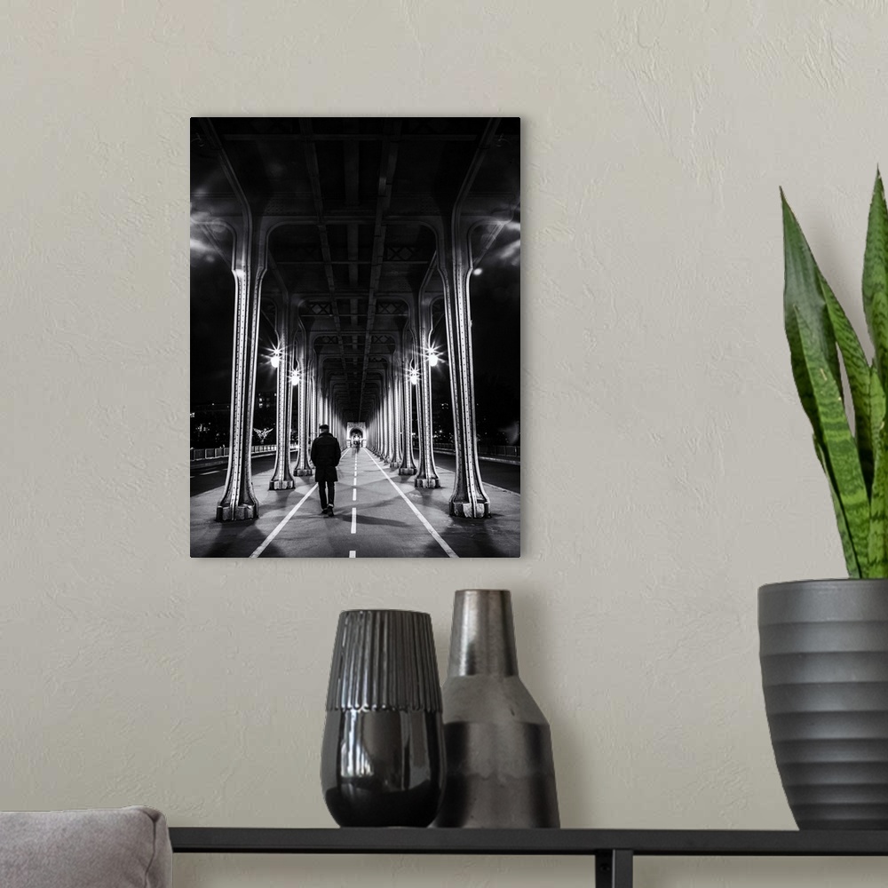 A modern room featuring Black and white photograph of a man walking under an overpass in Paris.