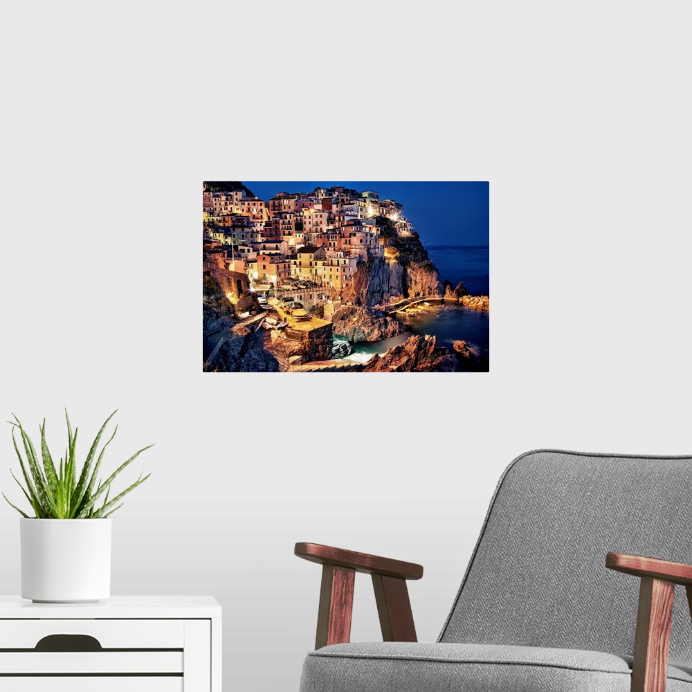 A modern room featuring Large photograph taken of homes and buildings sitting within the rocky cliffs of a city in Europe...