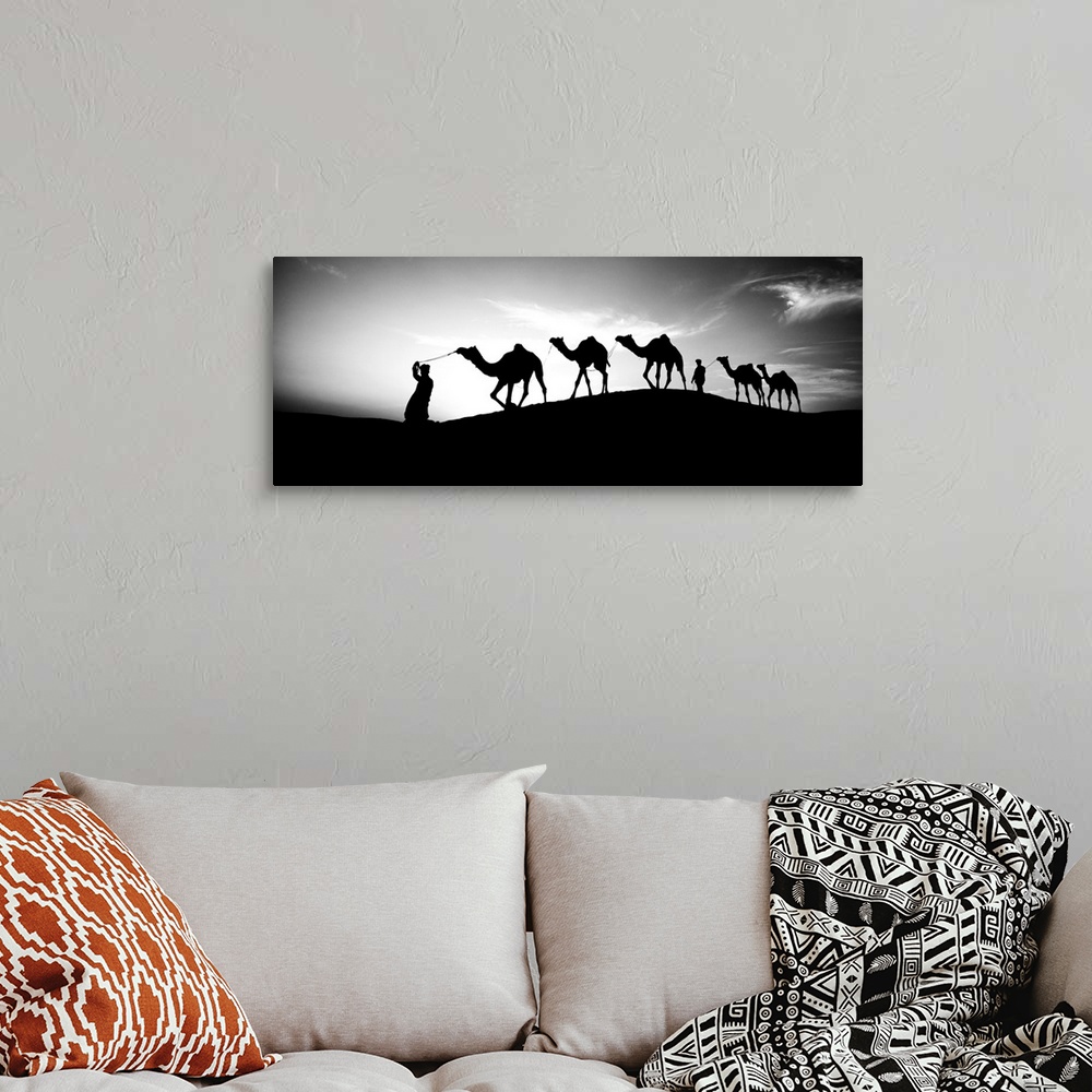 A bohemian room featuring Men walking camels through the desert in India