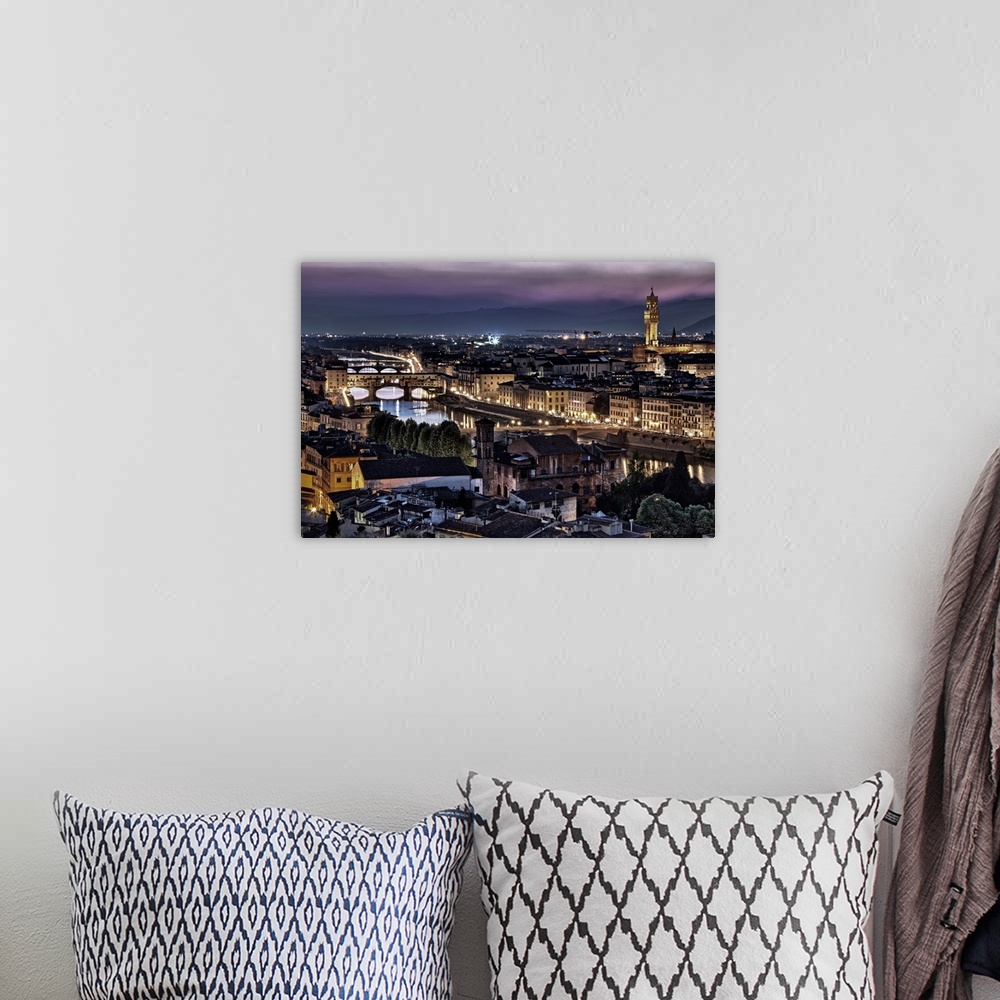 A bohemian room featuring Photograph of aerial view of city lit up and waterways under a dark cloudy sky.