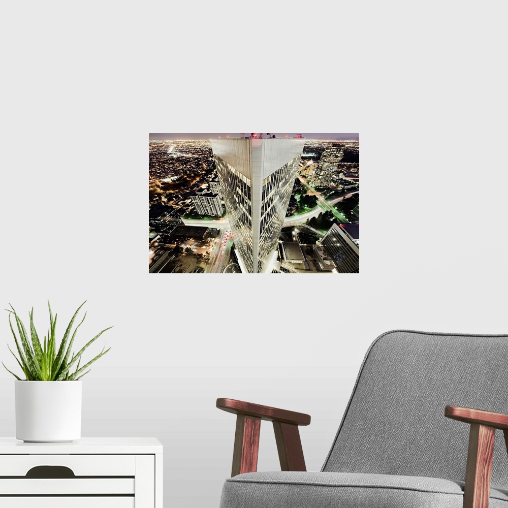 A modern room featuring Aerial photo of a triangular building in Los Angeles with the rest of LA lit up in the darkness b...