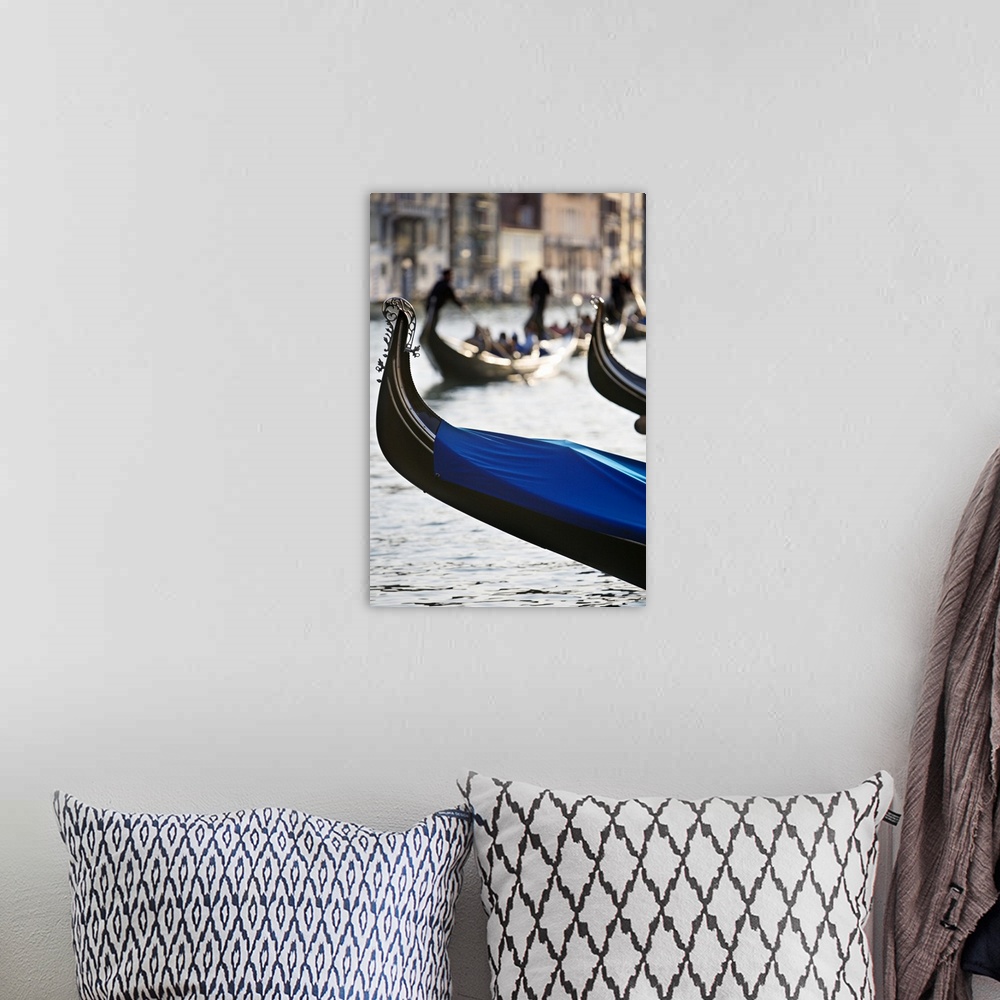 A bohemian room featuring Vertical photograph of the front tip of a Venetian gondola hanging over the water.  In the backgr...
