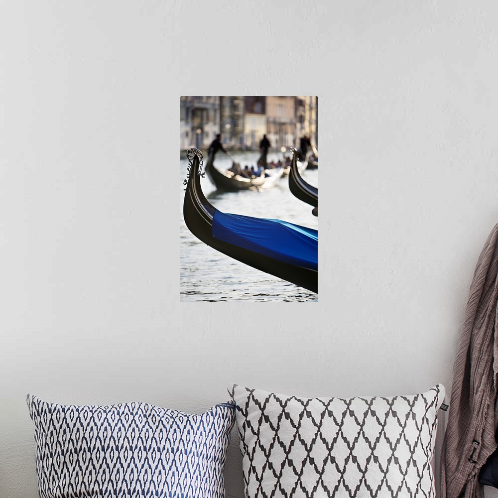 A bohemian room featuring Vertical photograph of the front tip of a Venetian gondola hanging over the water.  In the backgr...