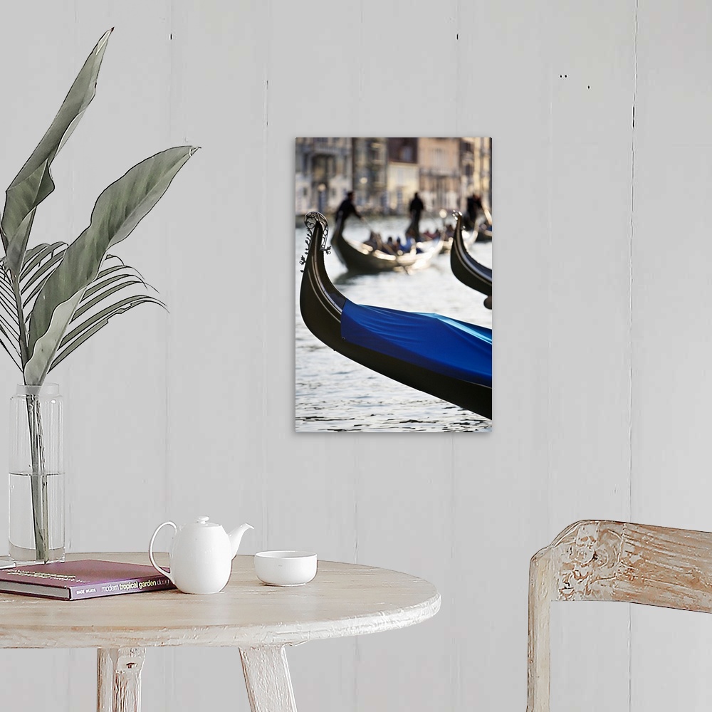A farmhouse room featuring Vertical photograph of the front tip of a Venetian gondola hanging over the water.  In the backgr...