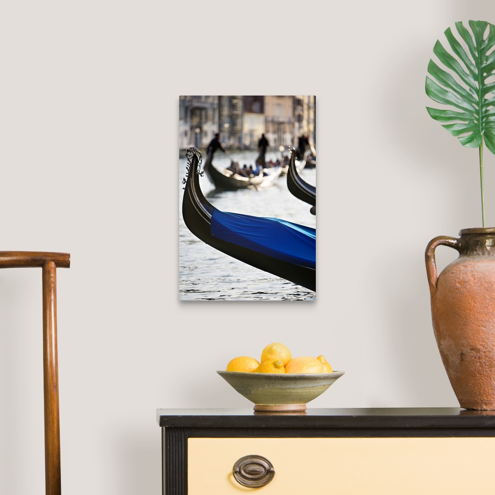 A traditional room featuring Vertical photograph of the front tip of a Venetian gondola hanging over the water.  In the backgr...