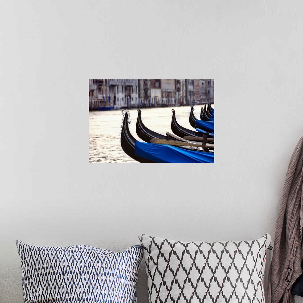 A bohemian room featuring Horizontal photograph on a big canvas of a row of the front ends of gondolas on the water.  A row...