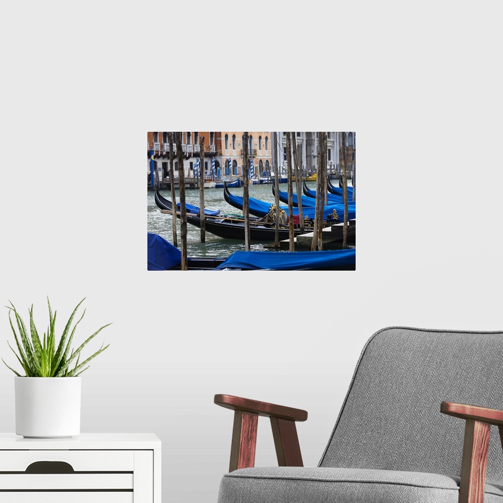 A modern room featuring Photograph taken of a river in Venice that is lined with gondola boats that are tied up and have ...