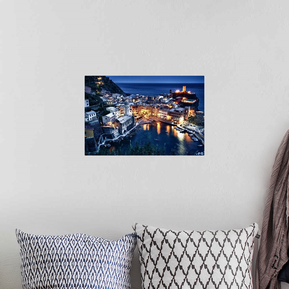 A bohemian room featuring Aerial view of a seaside town in Cinque Terre, Italy at night with houselights lighting up the ni...